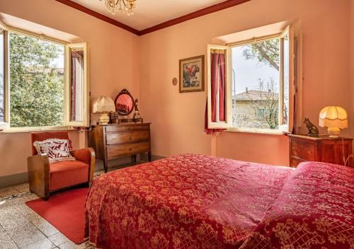 a bedroom with a bed and a chair and windows at 15 min da Montepulciano - Villa Chiara in Montefollonico