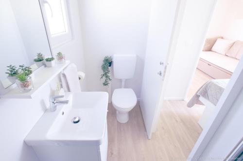 La salle de bains blanche est pourvue de toilettes et d'un lavabo. dans l'établissement Mobilheim Mate2, à Nin