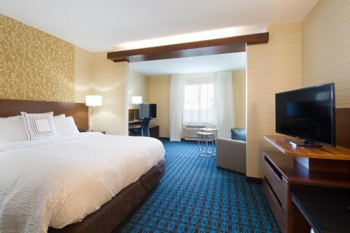 a hotel room with a bed and a flat screen tv at Fairfield Inn & Suites by Marriott Buffalo Amherst/University in Amherst