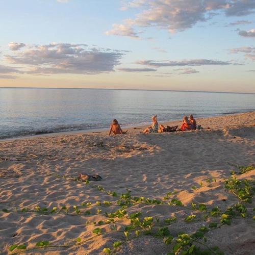 three people sitting in the sand on the beach at Cytyz Appart Hôtel in Mahajanga