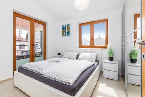 una camera bianca con un grande letto e finestre di Apartment Bailey a Pola (Pula)