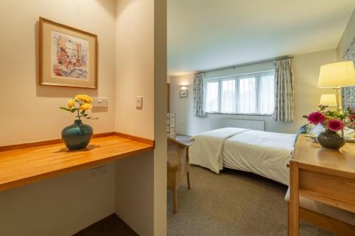 Un dormitorio con una cama y un escritorio con flores. en Stiffkey Hideaway, en Stiffkey