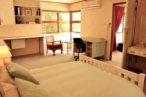 1 dormitorio con 1 cama y escritorio en una habitación en Carol Close Upstairs - A spacious apartment with a view, en Durbanville