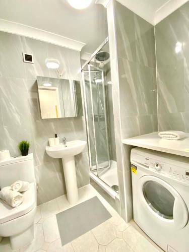 uma casa de banho com um lavatório e uma máquina de lavar roupa em Luxury Apt- Balcony-Kensington- 24 7 security em Londres
