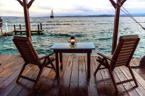 einen Tisch und zwei Stühle auf einer Anlegestelle mit Wasser in der Unterkunft Casa Acuario Boutique Hotel in Bocas del Toro