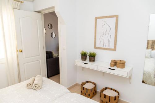 Habitación blanca con cama y espejo en Pedregalejo Madueño 10, en Málaga