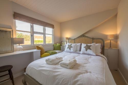 une chambre avec un lit blanc avec des serviettes dessus dans l'établissement Orchard Cottage, à Ringstead