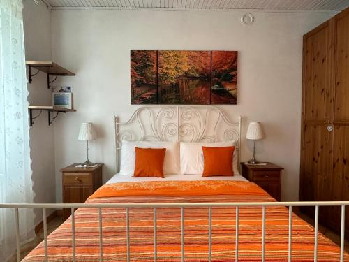ein Schlafzimmer mit einem Bett mit orangefarbenen Kissen und einem Gemälde in der Unterkunft Appartamento Arancione in Menaggio