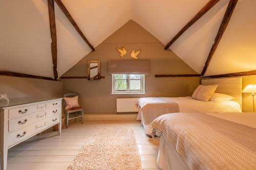 a attic bedroom with two beds and a window at Stockmans Cottage in Foulsham