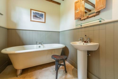 a bathroom with a tub and a sink at Stockmans Cottage in Foulsham