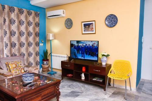 a living room with a tv and a yellow chair at The Pearl Apartment Hammam Sousse WIFI in Sousse