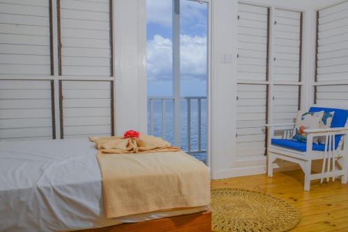 um quarto com uma cama, uma cadeira e uma janela em Begona Cliff Hotel em Negril