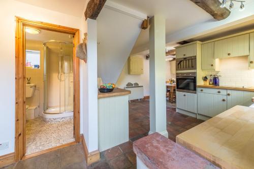 uma cozinha com armários verdes e um piso em plano aberto em Newgates Cottage em Wells-next-the-Sea