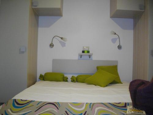 a bed with green pillows and two lights on the wall at Mobilhomes SKALLA CZ in Martinsicuro