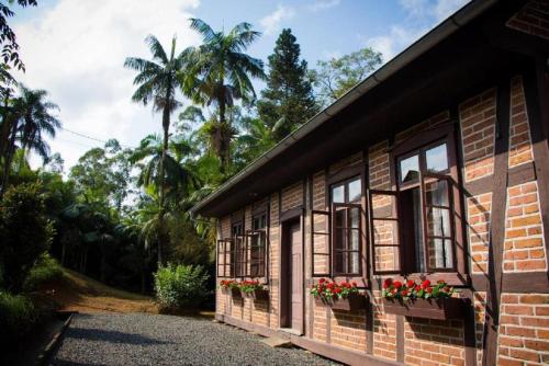 Pousada Casa Wachholz - Rota do Enxaimel في بوميرودي: منزل من الطوب مع نوافذ والزهور عليه