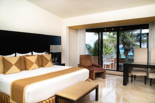 a hotel room with a bed and a desk and a balcony at Grand Oasis Tulum Riviera - All Inclusive in Akumal