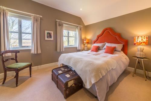 um quarto com uma cama grande e uma cadeira em Owl Cottage Woodside em Burnham Market