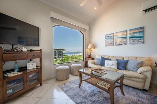 a living room with a couch and a large window at Monte Perla Condo at Tamarindo in Tamarindo