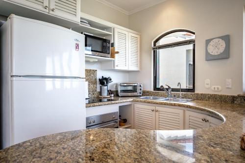 a kitchen with a white refrigerator and a sink at Monte Perla Condo at Tamarindo in Tamarindo