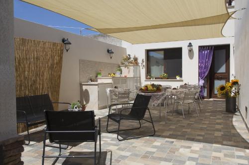 eine Terrasse mit Stühlen, einem Tisch und einer Küche in der Unterkunft B&B Piano di Sopra in San Vito lo Capo