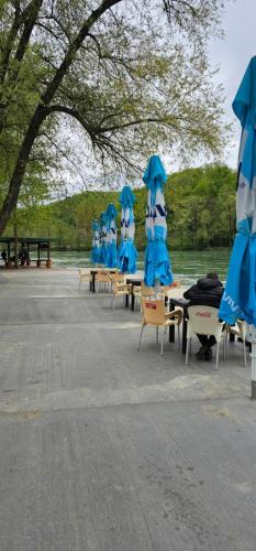 a group of tables and chairs with blue umbrellas at Etno selo Bok in Vrhpolje
