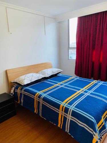 ein Schlafzimmer mit einem Bett mit einer blauen Decke und einem Fenster in der Unterkunft Bogotá Kings 401 in Bogotá