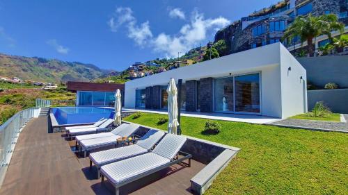 a row of chaise lounge chairs on a patio with a house at Villa Blue Horizon by LovelyStay in Tábua