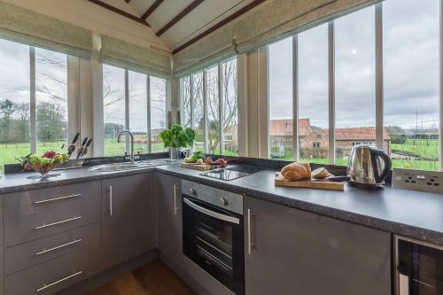 a kitchen with a counter with a sink and windows at The Signal Box in Melton Constable