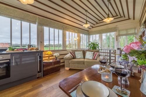 a kitchen and living room with windows and a couch at The Signal Box in Melton Constable