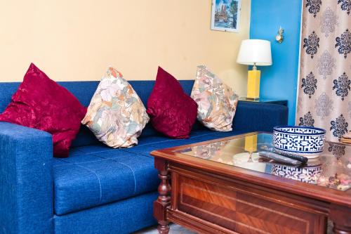 a blue couch with four red pillows on it at The Pearl Apartment Hammam Sousse WIFI in Sousse