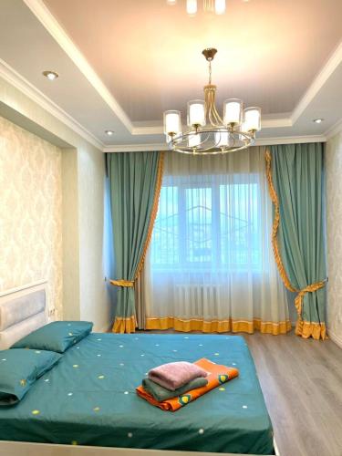 1 dormitorio con 1 cama verde grande con lámpara de araña en Elite apartment in street Moskovskay 191, en Bishkek