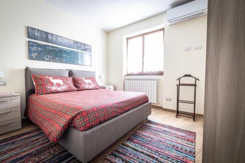 Schlafzimmer mit einem Bett mit einer roten Decke und einem Teppich in der Unterkunft La Casa sul Fiume in Chiavenna
