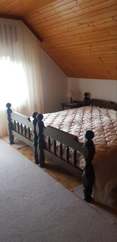 a wooden bed in a bedroom with a wooden ceiling at Apartma Sabatuš in Bohinj