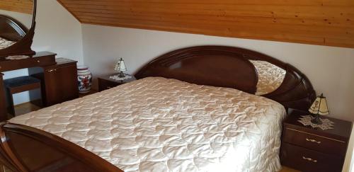a bedroom with a large bed with a wooden headboard at Apartma Sabatuš in Bohinj