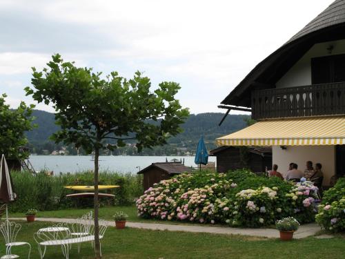 a group of people sitting outside of a house with flowers at Seehaus Edith in Maria Wörth