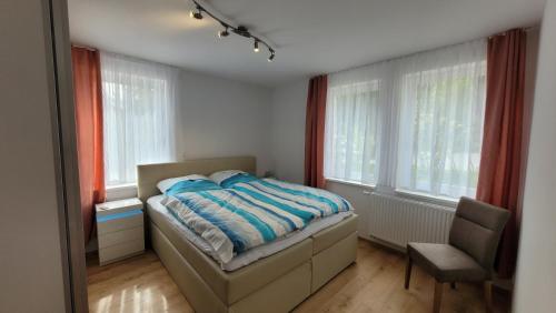 a bedroom with a bed and a chair and windows at Sachsentraum in Reichenbach im Vogtland