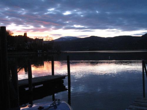 a sunset over a lake with a dock in the water at Seehaus Edith in Maria Wörth
