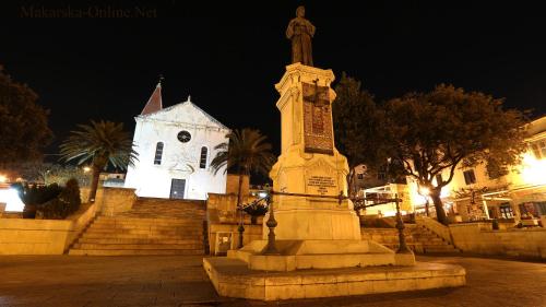 a monument in front of a church at night at Apartments Villa Flamingo in Makarska