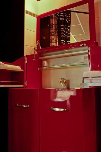 - une cuisine rouge avec un évier et un miroir dans l'établissement BOUTIK Hotel O'Domaine, à Chis