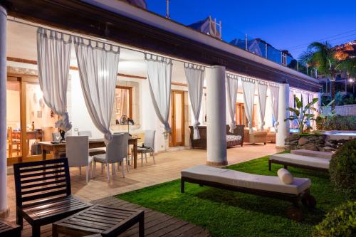 a patio with white curtains and a table and chairs at Villa Zagara Garden Spectacular Sea View in Taormina in Taormina