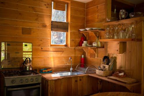 a kitchen with wooden walls and a stove and a sink at Haiku Cabañas Panorámicas in San José de Maipo