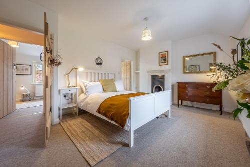 a bedroom with a bed and a dresser and a mirror at Chiffchaff Cottage in West Raynham