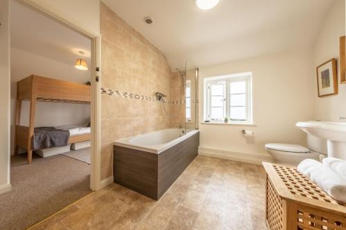 a bathroom with a tub and a toilet and a sink at Chiffchaff Cottage in West Raynham