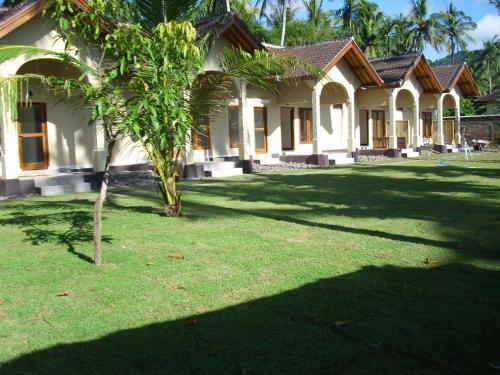 a house with a palm tree in front of it at Yuli's Homestay in Kuta Lombok