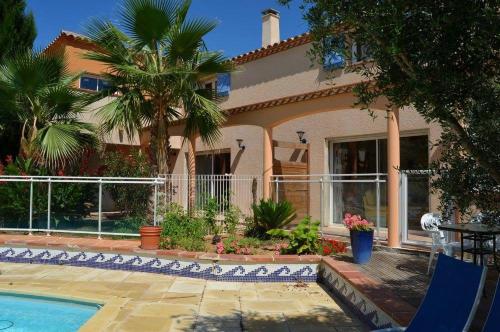a house with a swimming pool and palm trees at Au bon vivre in Vivès