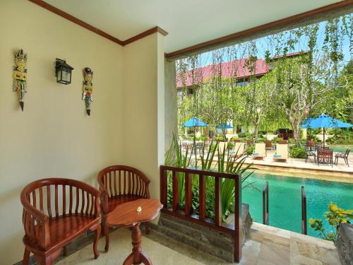 a room with two chairs and a table and a pool at The Grand Bali Nusa Dua in Nusa Dua