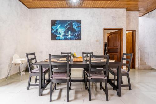 a dining room table with chairs and a painting on the wall at Inari Villa Nusa Dua in Nusa Dua