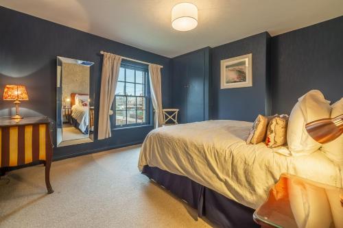 a bedroom with blue walls and a bed and a mirror at 2 Dix Cottages in Thornham