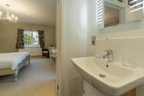a bathroom with a sink and a bed in a room at 2 Dix Cottages in Thornham