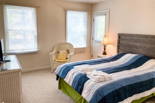 a bedroom with a bed and a chair and windows at Cherished Memories in Nags Head
